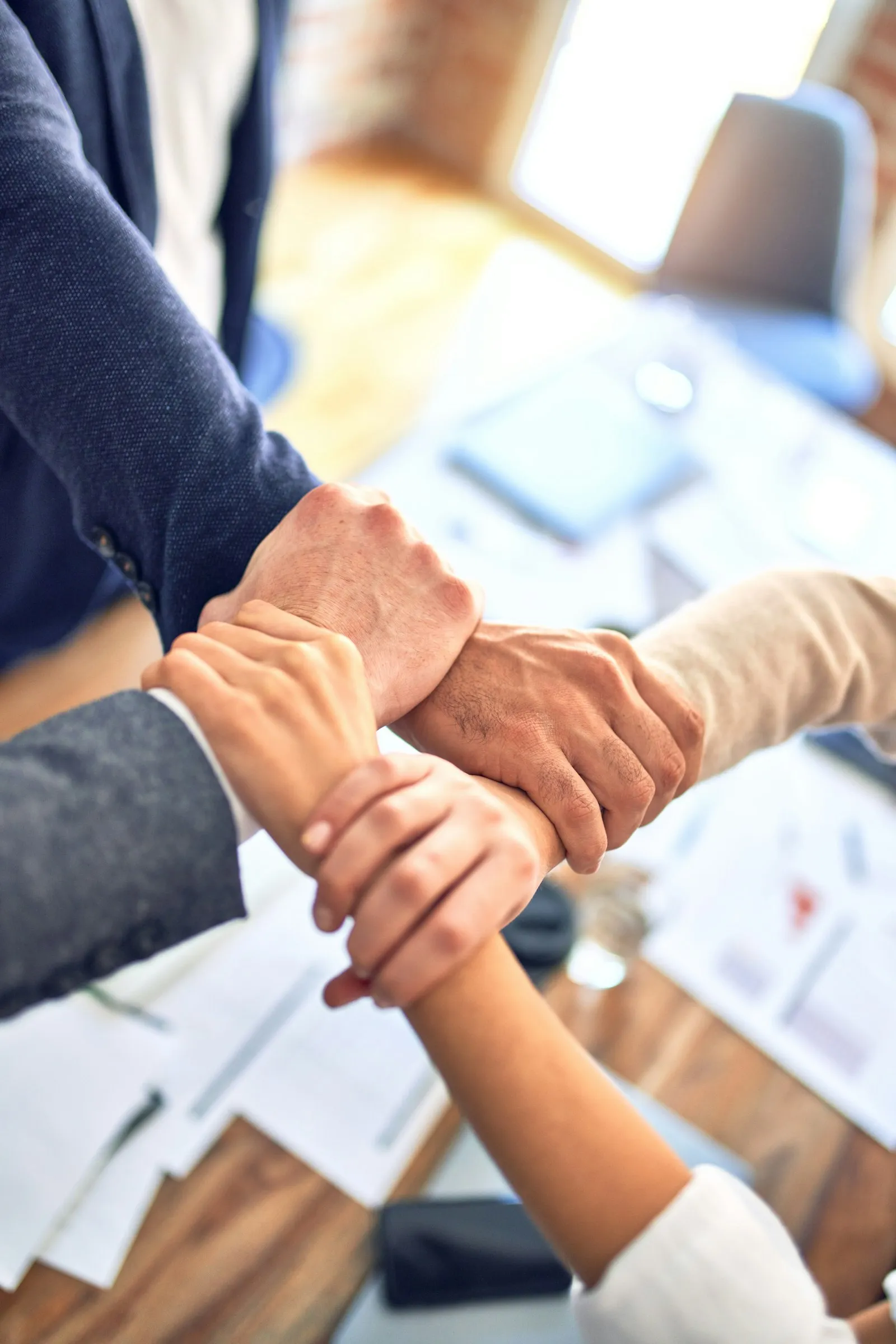 Colleagues stacking hands together over a desk after closing a deal