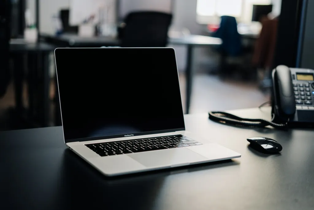 Laptop and desk phone on a dark desk