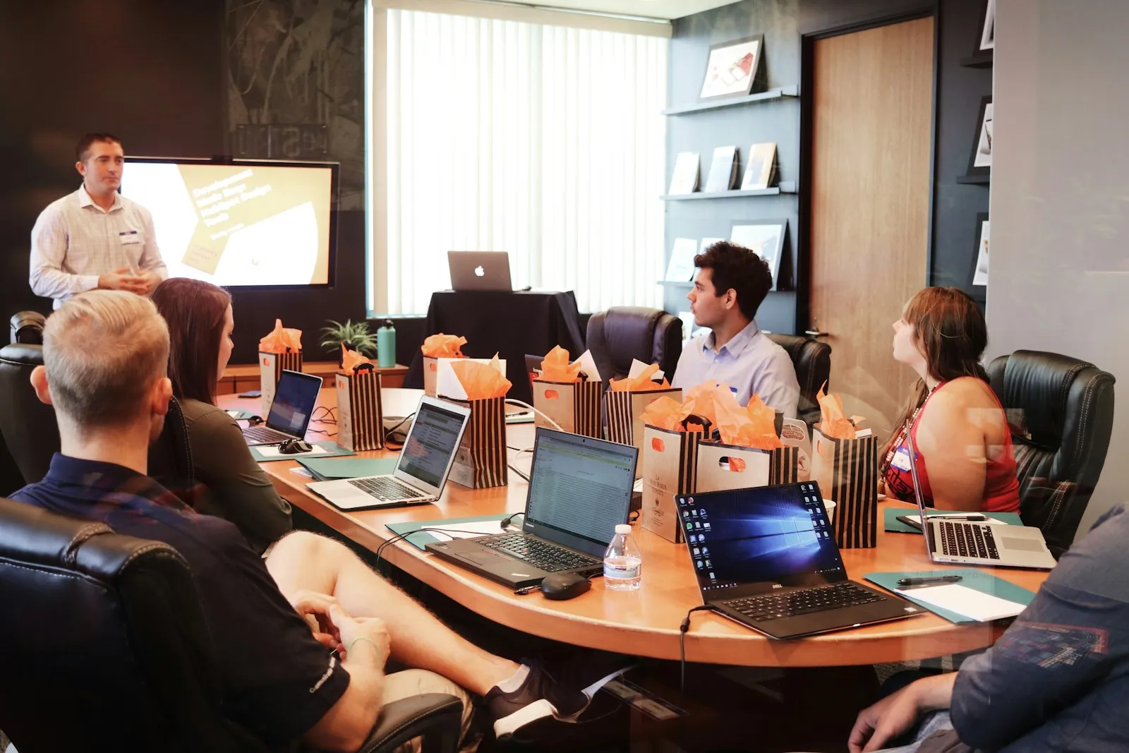 Presenter leading a training session for a room of professionals with laptops