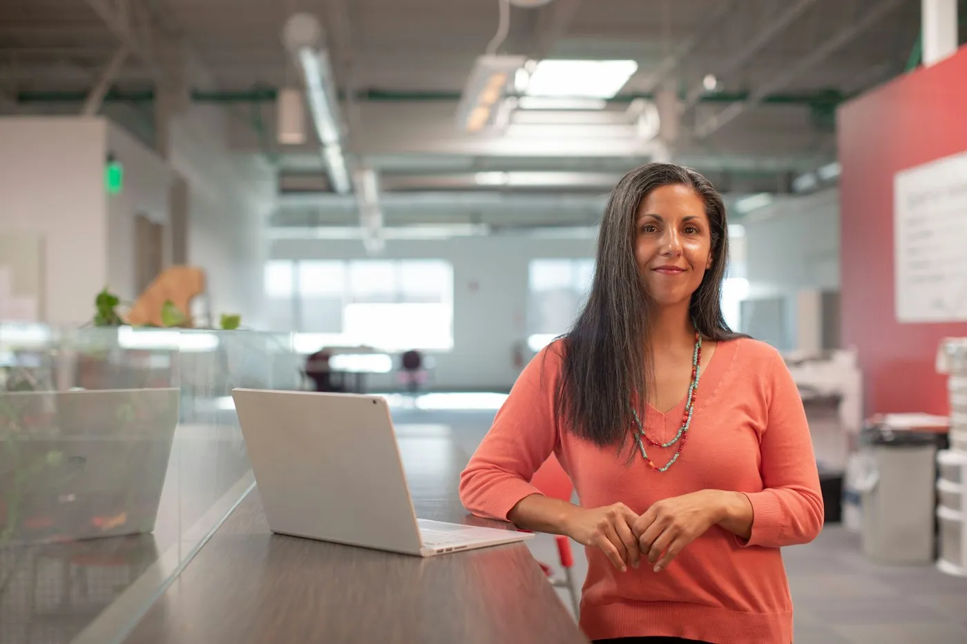 Smiling professional at her desk in a bright open-plan office