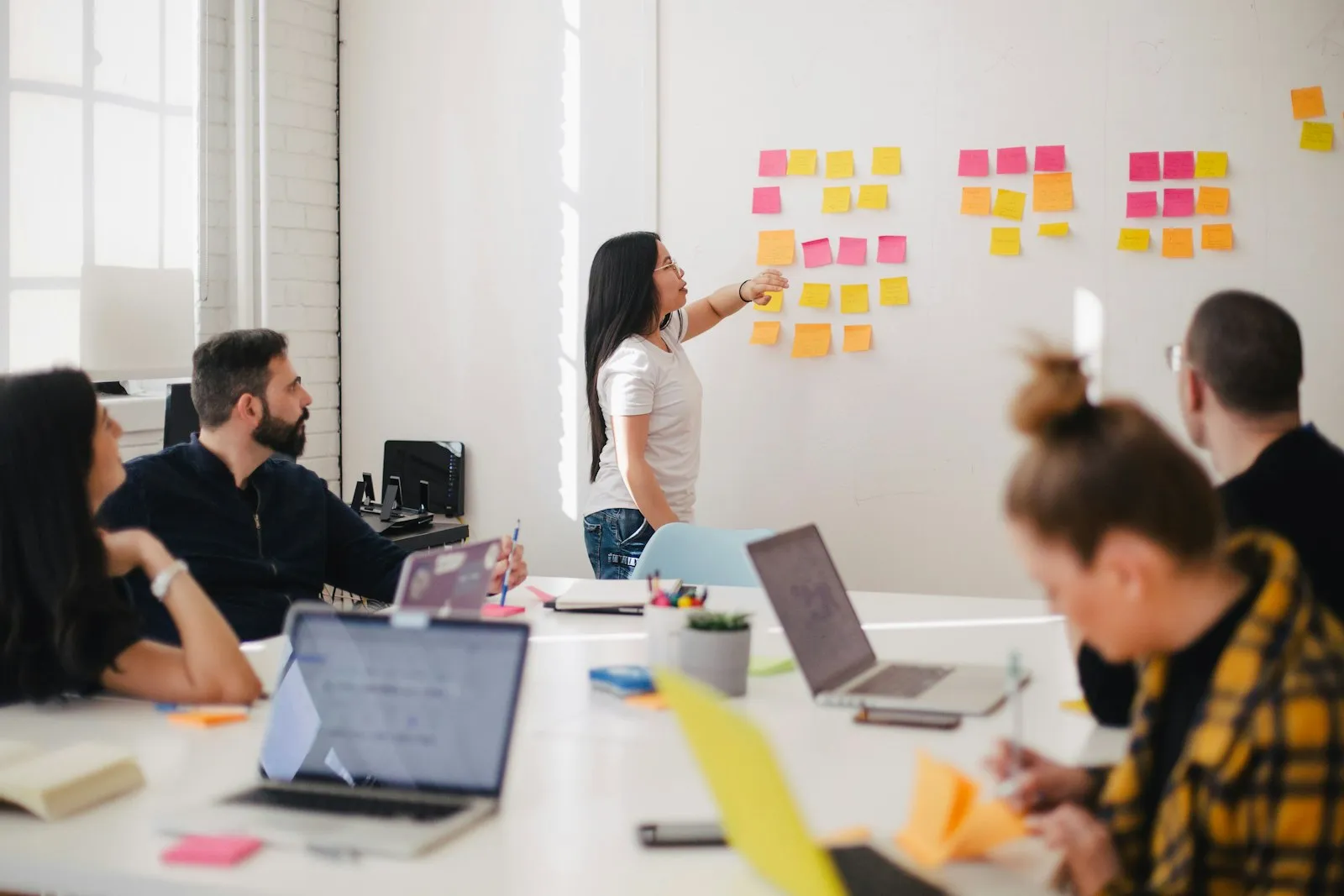 Team planning with sticky notes on a glass wall during a meeting