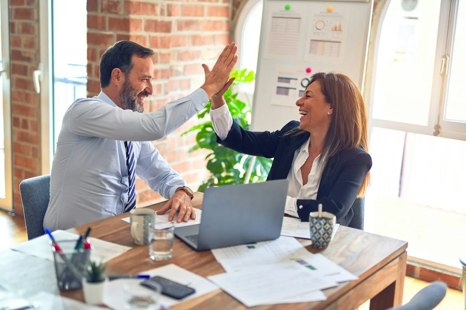 Two colleagues celebrating with a high five after a successful client call